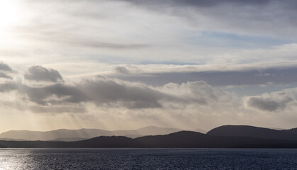 Wall Mural - Serene Coastal Landscape with Clouds and Sun Rays over the Ocean
