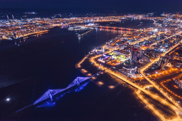 Aerial top view city Krasnoyarsk bridge through Yenisei river evening with neon light