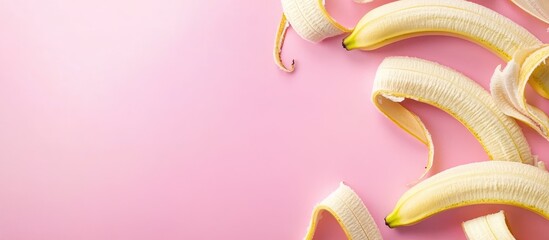 Wall Mural - Peeled bananas scattered on a soft pink background offering ample empty space for text or design elements in a bright aesthetic setting