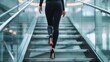 © Mega - Woman in black pantsuit ascending modern glass staircase, red soles visible.