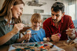 © La Famiglia - Family teamwork as they dip Easter eggs into dye and add colorful patterns