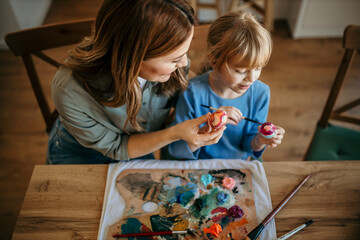 Wall Mural - Mother and daughter painting Easter eggs while surrounded by festive decor