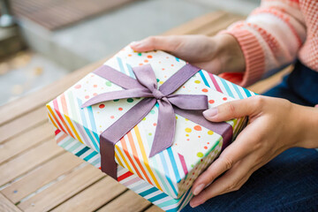 a person holding a gift box on a bench