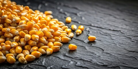 Poster - A close-up view of a pile of yellow corn kernels on a black stone surface. The kernels are arranged in a random pattern, with some scattered around the pile.