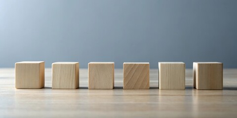 Aufkleber - A Row of Six Blank Wooden Cubes on a Light Brown Wooden Tabletop Against a Neutral Grey Background