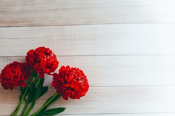 Wall Mural - A vibrant arrangement of red flowers on a light wooden background.