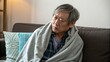 © IbragimovN - Elderly man resting peacefully on sofa wrapped in blanket