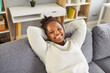 © Studio Romantic - Young african american woman enjoys relaxing on new soft couch in living room, calm female crossing hands behind head, taking a break during work day at home, stress free lady good mood smile