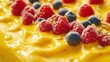 © milenialdesastudio - Close-up of mango dessert topped with raspberries, blueberries, and seeds.