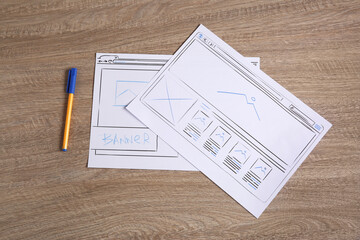 Leinwandbilder - Developing UI design. Sketches of website wireframes and pen on wooden table, top view