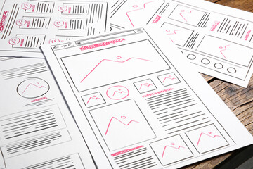 Leinwandbilder - Developing UI design. Sketches of website wireframes on wooden table, closeup