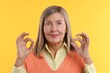 © New Africa - Senior woman showing okay gesture on yellow background