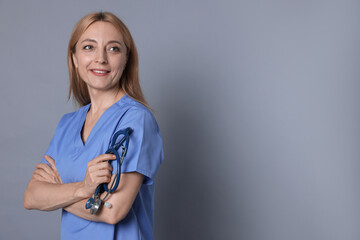 Wall Mural - Doctor with stethoscope on gray background, space for text