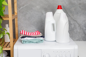 Wall Mural - Laundry detergents in bottles and stacked clean clothes on washing machine indoors