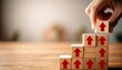 © Yelloone - A hand places a block with an upward arrow on a stack of wooden blocks, symbolizing growth and progress in a minimalist setting.