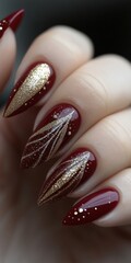 Wall Mural - Close-up of elegant burgundy nails with gold leaf design and glitter accents.