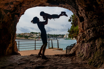 Wall Mural - A woman is holding a child in her arms while standing in front of a large rock