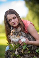 Wall Mural - Portrait of a young beautiful long-haired girl, in light clothes in the summer, in the park with a cat.