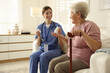 © New Africa - Caregiver giving pills to senior woman on sofa indoors. Home health care service