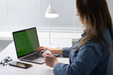 Poster - A woman works on a laptop at a bright, organized desk with modern decor, focused and comfortable. The inspiring lighting enhances her productive environment, merging technology and design