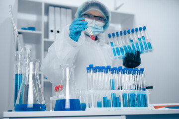 Aufkleber - A dedicated scientist is currently working in a laboratory, meticulously analyzing blue liquid samples that are placed in various test tubes as part of an important research study