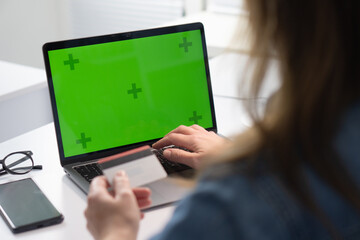 Poster - A person is actively using a laptop that has a green screen background, which is intended for display or mockup purposes during their work session, emphasizing a modern and productive workspace setup