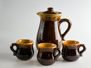 Wall Mural - Ceramic dishes on a white background, a clay teapot and three cups