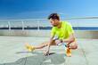 © muse studio - Man stretches on sunlit waterfront promenade during daytime fitness routine