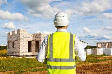 Poster - man builder with his back to camera. architectural engineer in reflective vest. builder near country