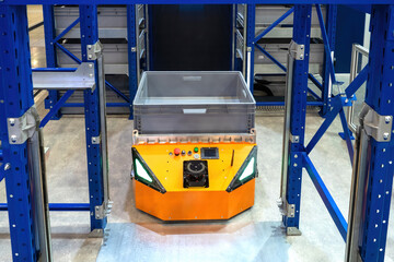 Poster - Warehouse robot. Automated guided vehicles. AGV among warehouse racks. Autonomous mobile robot. Storage machines in distribution center. Warehouse robot for transporting boxes. Modern storage tech