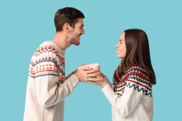 Wall Mural - Beautiful young couple with gift box on blue background. Valentine's day celebration