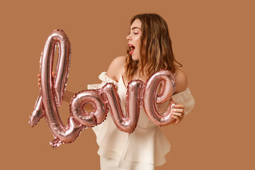 Sticker - Surprised young woman with word LOVE made of balloons on brown background. Valentine's Day celebration