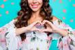 © deagreez - Half face cropped portrait of cute delicate shine lovely romantic woman showing love symbol, heart shape with fingers isolated on shine turquoise background