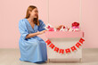 © Pixel-Shot - Young woman and paper booth with gift boxes near pink wall. Valentine's Day celebration