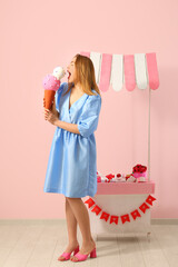 Sticker - Young woman with ice cream figure and paper booth near pink wall. Valentine's Day celebration