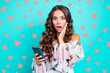 © deagreez - Portrait of worried lady with wide open mouth and big eyes isolated on bright teal background with modern blue smartphone in hands touch cheek by palm