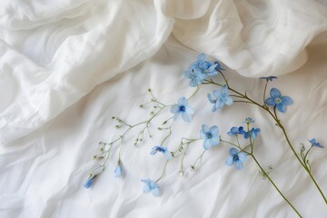 Aufkleber - Delicate blue flowers arranged on soft white fabric create a serene and tranquil setting ideal for floral design inspiration