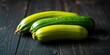 © Vibrant Visions Pixe - Three vibrant green zucchini arranged on a dark wooden surface