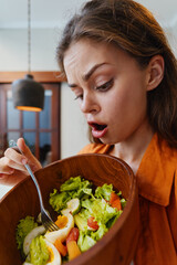 Canvas Print - Surprised woman looking at a healthy salad with eggs, expressing shock and curiosity, in a bright kitchen with warm colors