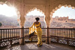 © Matteo Colombo - Indian woman with yellow saree standing inside an arched pavilion, Amer Fort, Rajasthan, India