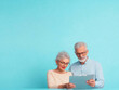 © Jirawatfoto - Senior couple reviewing documents together against bright blue background