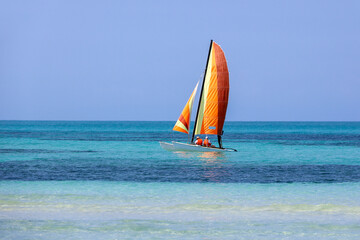 Sailboat with couple in life vests on blue ocean surface. Background for holidays on a sunny beach