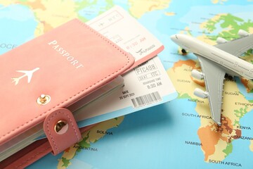 Wall Mural - Passport with tickets and plane model on world map, closeup