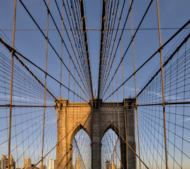  Brooklyn Bridge close up detail looking up at suspension cables at sunrise (beautiful landmark travel tourism destination in NYC) iconic New York City attraction over east river downtown Manhattan USA