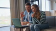 © stockbusters - Laughing friends talking virtual meeting by laptop relaxing at apartment closeup