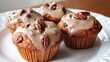 © Seyyar - Citrus glazed sweet potato muffins topped with pecans and raisins on a white plate illuminated by natural light