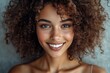 © olegganko - Beautiful woman with curly hair smiling against a neutral background during daylight