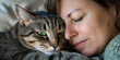 © Easy - A woman curls up in bed, peacefully sleeping with her grey tabby cat nestled beside her. Sunlight gently filters through the window, creating a warm atmosphere.