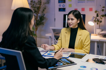 Aufkleber - Two businesswomen work late in the office, analyzing financial reports and discussing strategies during a productive meeting