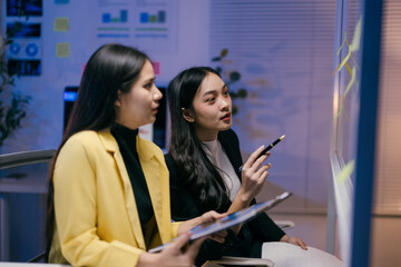 Aufkleber - Two young businesswomen are working late in the office, brainstorming ideas using sticky notes on a glass partition and a tablet, discussing strategies and solutions for their project